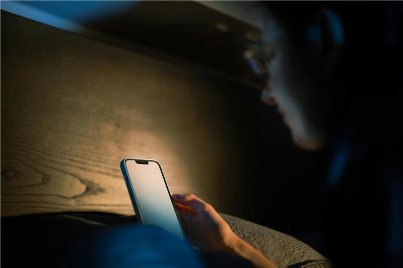 Teenager using a smartphone late at night, highlighting sleep and screen time concerns.